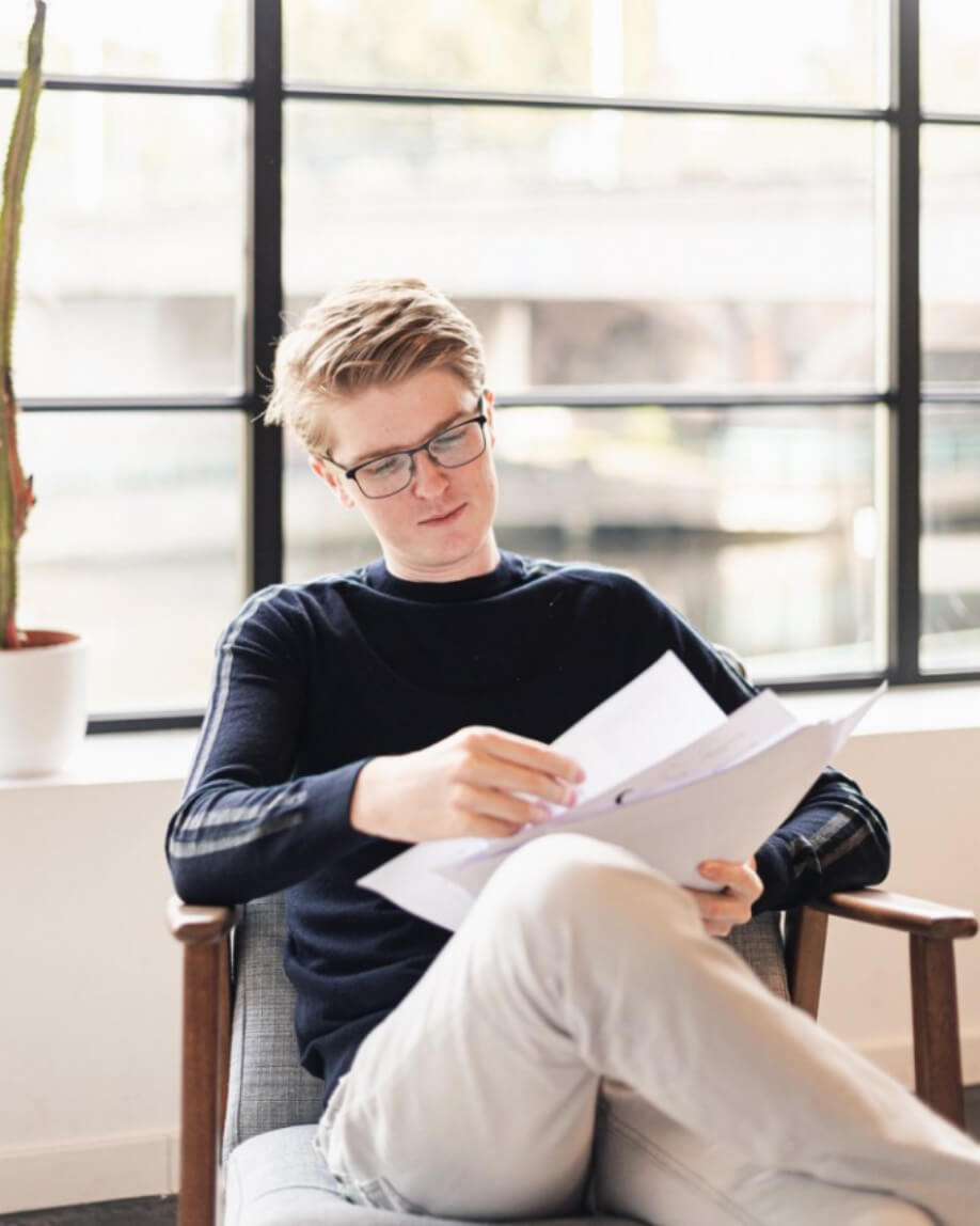 Thomas in a chair casually reading some papers